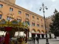 Carosello colorato e albero di Natale in piazza, scorci di cosa vedere a Treviso con palazzi storici e gente che passeggia.