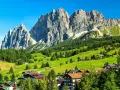 Un viaggio da Venezia a Cortina: verdi pascoli, boschi rigogliosi e imponenti vette dolomitiche incorniciano un villaggio alpino.