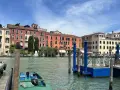 Canale di Venezia con edifici colorati e pontili blu. Per sapere how to get from Venice train station to San Marco, prendi un vaporetto.