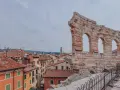 Resti antichi dell'Arena di Verona, testimoni di quanti anni ha l'Arena di Verona, si stagliano su un panorama di tetti rossi.