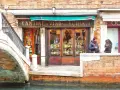 Coppia davanti a una delle tipiche osterie a Venezia, con bottiglie di vino in esposizione.