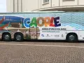 Bus turistico con grafica promozionale di Caorle, borgo storico sul mare. Immagini di spiaggia, mare e una donna in bikini.