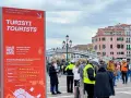 Cartello rosso a Venezia per il contributo accesso turisti, con date e QR code. Persone in fila sullo sfondo.