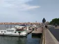 Un vaporetto attracca a Chioggia, con la città sullo sfondo e una strada trafficata.