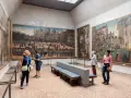 Visitanti ammirano grandi dipinti storici in uno dei musei d'arte a Venezia.