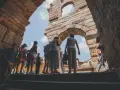 Turisti esplorano l'Arena di Verona, un'antica struttura che ricorda il Colosseo, sotto un cielo azzurro.