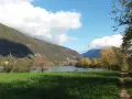 Sentiero per passeggiate in montagna Veneto, con lago, colline verdi e cielo azzurro con nuvole bianche.
