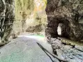 Gola rocciosa con acqua cristallina che ricorda il lago del Mis. Un sentiero scavato nella roccia conduce verso un'apertura luminosa.