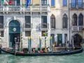 Gondola con gondoliere e passeggeri naviga lungo un canale a Venezia. Esplorare Venezia a piedi è un'esperienza, ma una gondola offre una prospettiva unica.