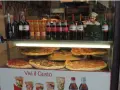 Vetrine con pizze, bottiglie di vino e bibite, un cartello "PIZZA DA € 2.50" e un cuoco decorativo. Sembra un ottimo posto per trovare le migliori pizzerie a Venezia.