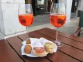 Due calici di Spritz e cicchetti, un classico per gli aperitivi a Venezia, su un tavolino di legno.