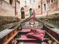 Gondola con cuscino rosso, pronta per un giro romantico a Venezia, città dell'amore.