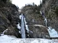 Cascate in Veneto, con rocce innevate e ghiaccio che scende lungo i fianchi della montagna.