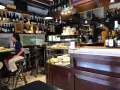 Interno di un'osteria al cicheto a Venezia, con bottiglie di vino, cibi in vetrina e persone sedute al bancone.