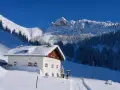 Rifugio innevato nelle Dolomiti, ideale per ciaspolate invernali. Montagne maestose e boschi coperti di neve.
