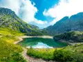 Sentiero panoramico verso un lago alpino turchese, incorniciato da montagne maestose. Un vero gioiello dell'alta via Dolomiti più bella.