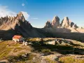 Rifugio con tetto rosso e montagne imponenti, un'oasi di pace tra i rifugi Dolomiti Bellunesi facili, ideale per un'escursione panoramica.
