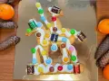 San Martino, dolce veneziano: biscotto decorato con glassa bianca, caramelle colorate e piccoli cioccolatini a forma di botte, su sfondo dorato.