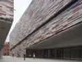 Il museo M9 a Mestre, con la sua facciata a listelli colorati, accoglie visitatori sotto un'imponente pensilina in cemento.