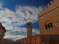 Torre dell'Orologio e palazzi storici a Treviso, un viaggio da Padova a Treviso sotto un cielo azzurro e nuvoloso.