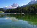 Il **lago di Misurina** incanta con le sue acque verdi e le montagne maestose. Barchette a remi solcano la superficie, riflettendo il cielo azzurro e la foresta di abeti.