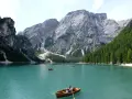 Lago turchese con barche a remi e maestose montagne veneto sullo sfondo.
