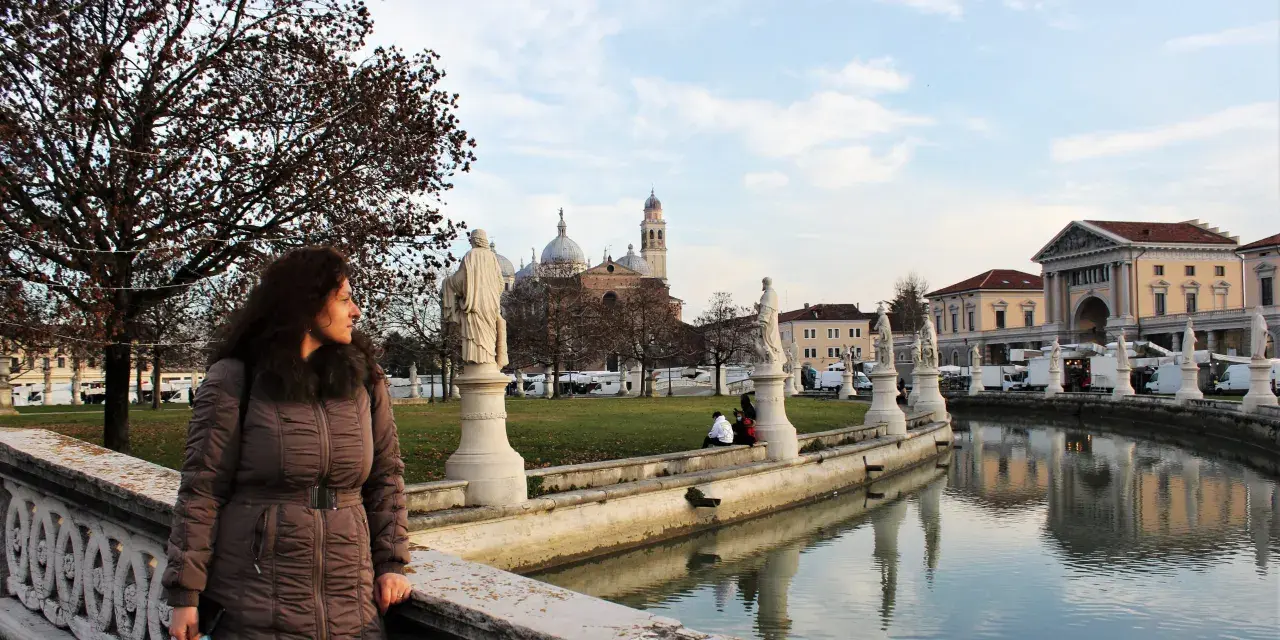 Donna guarda il canale con statue e palazzi a Padova, ideale per visite guidate.