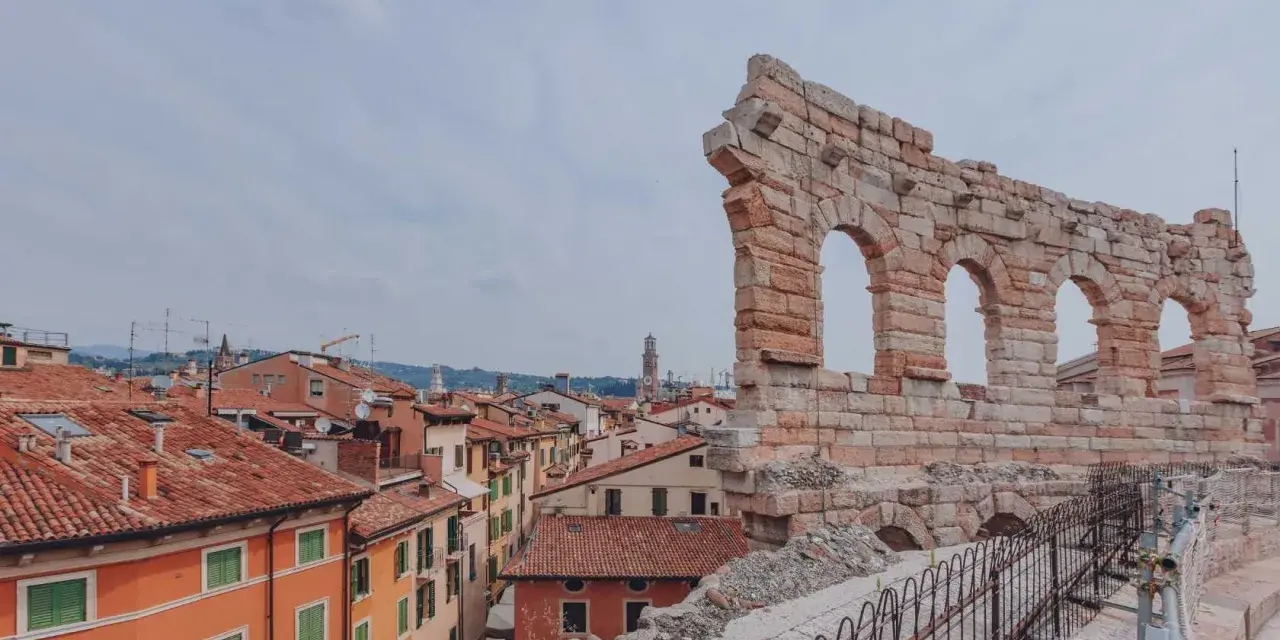 Resti antichi dell'Arena di Verona, testimoni di quanti anni ha l'Arena di Verona, si stagliano su un panorama di tetti rossi.