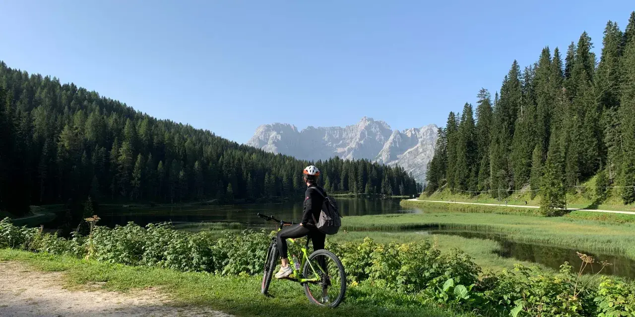 Ciclista ammira il panorama sul lago e le montagne lungo la ciclabile Auronzo Misurina.