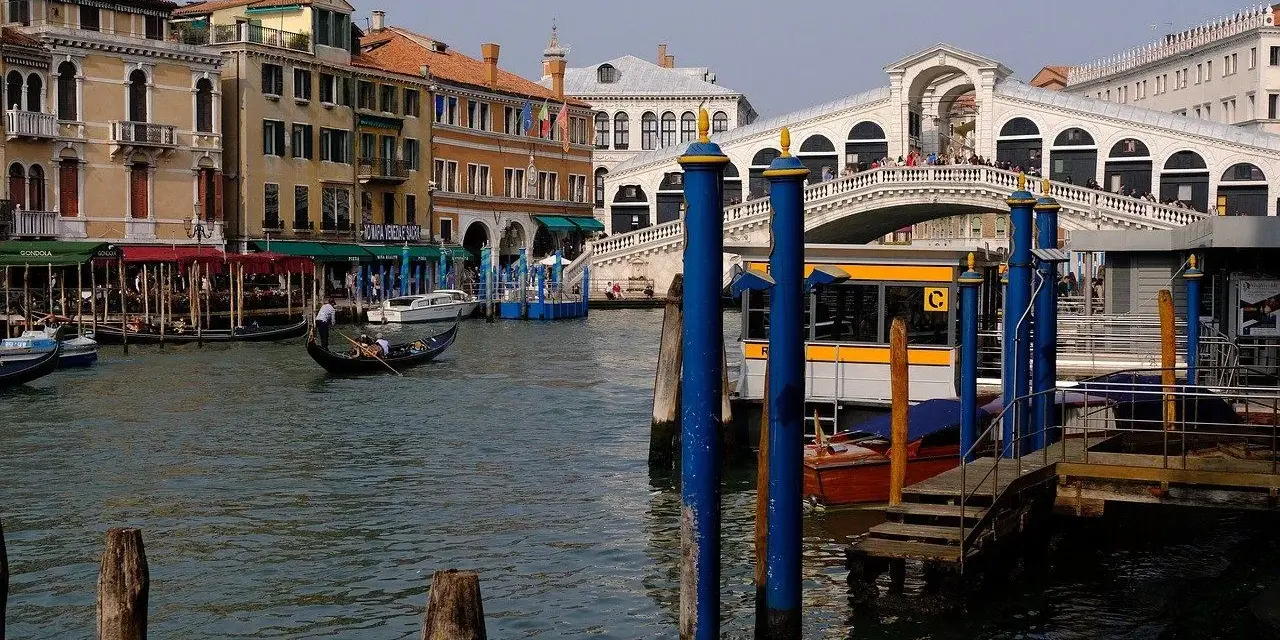 Gondola scivola sul Canal Grande, con il Ponte di Rialto e il vivace mercato di Rialto sullo sfondo.