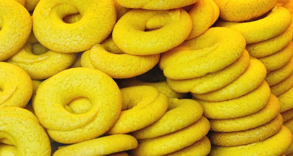 Una pila di dolcetti veneziani gialli, a forma di ciambella, con una texture leggermente ruvida.
