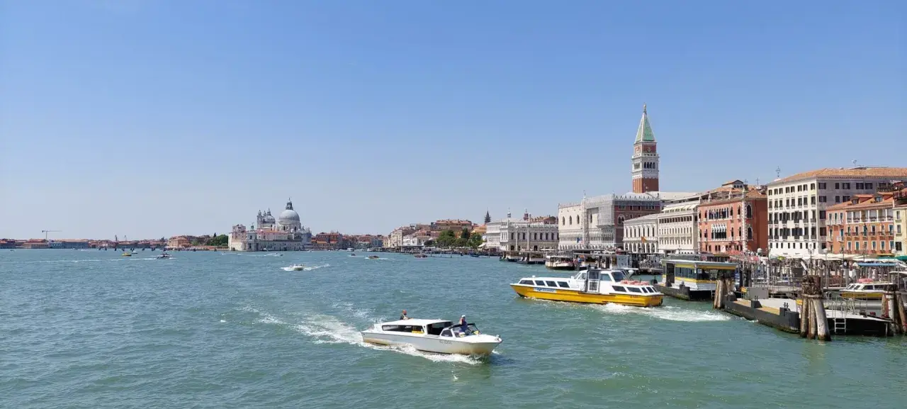Venezia: il Canal Grande con la linea 1 vaporetto venezia fermate, barche e palazzi storici sotto un cielo azzurro.