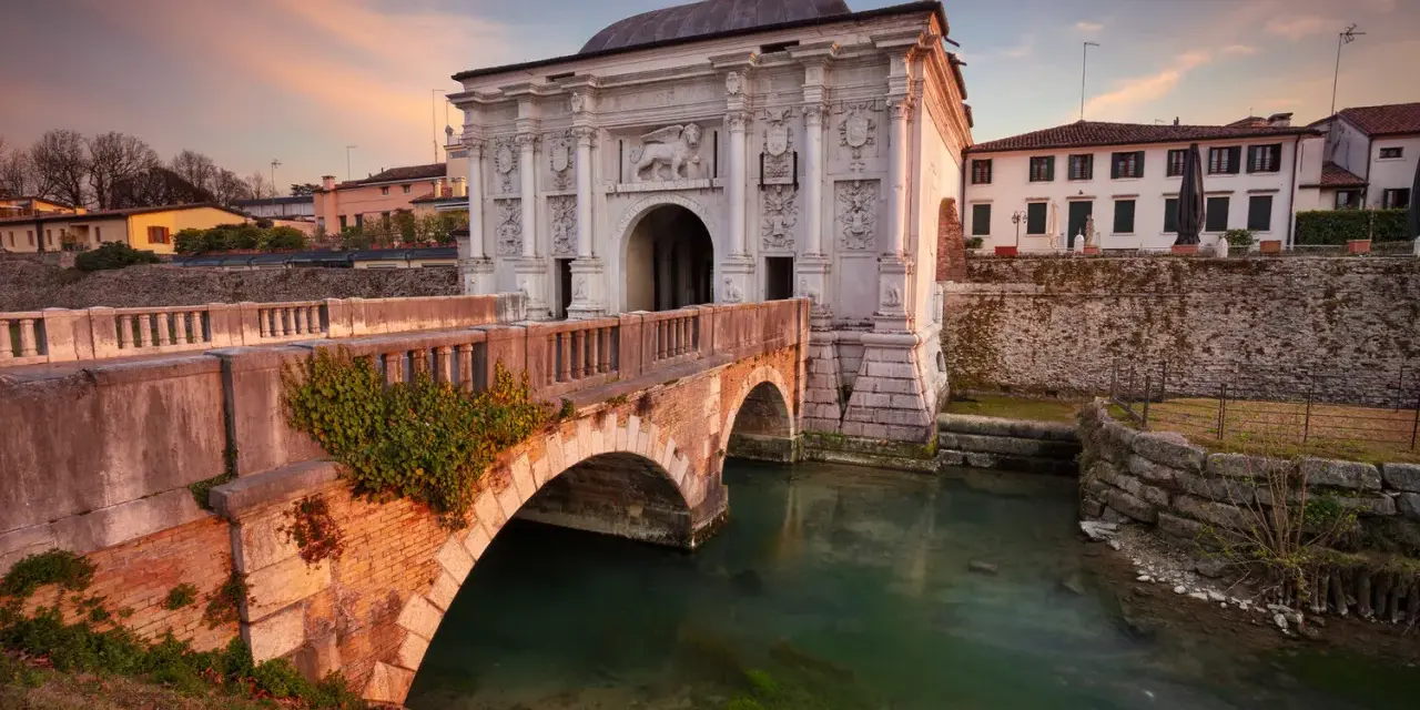 Porta San Tomaso a Treviso, un'idea per cosa fare a Treviso nel weekend. Un ponte in mattoni attraversa un canale con acqua verde.