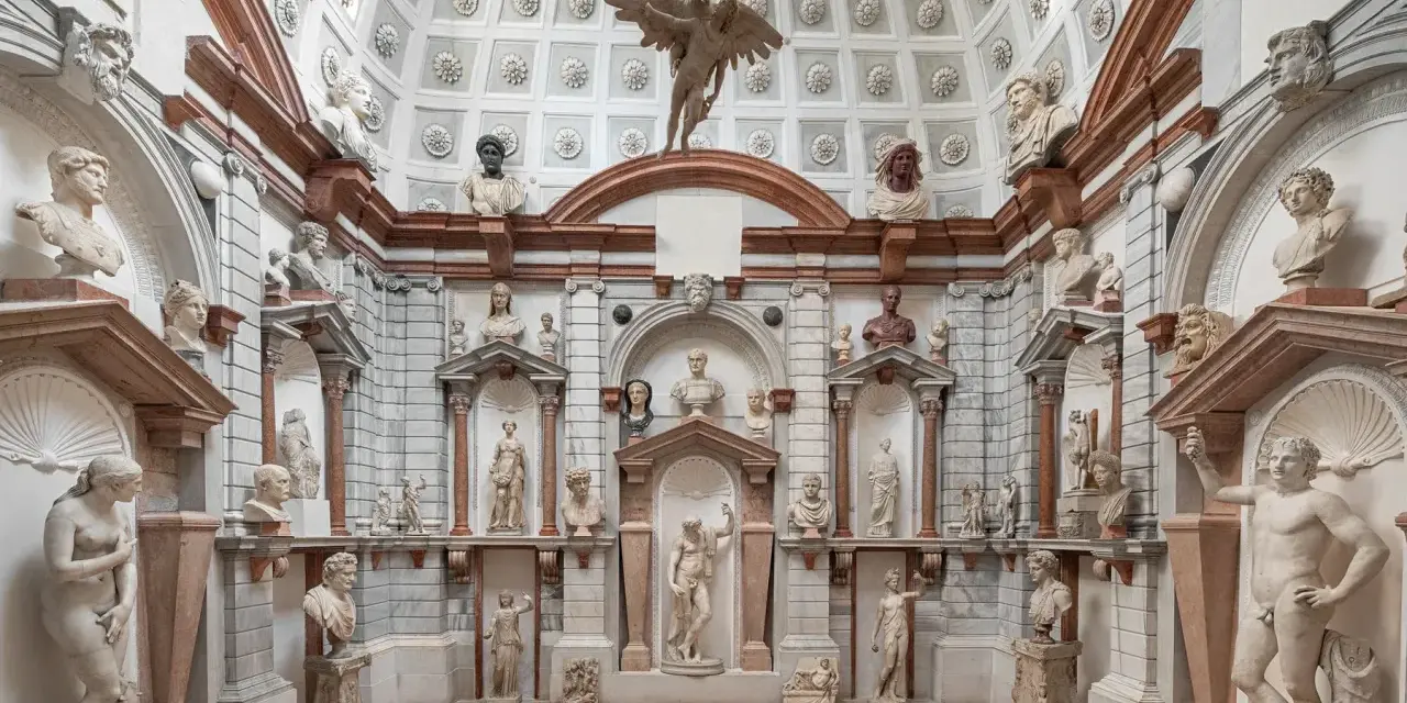 Interno del Palazzo Grimani a Venezia, un tripudio di sculture classiche e busti antichi che adornano nicchie e mensole, creando un'atmosfera di maestosa antichità.