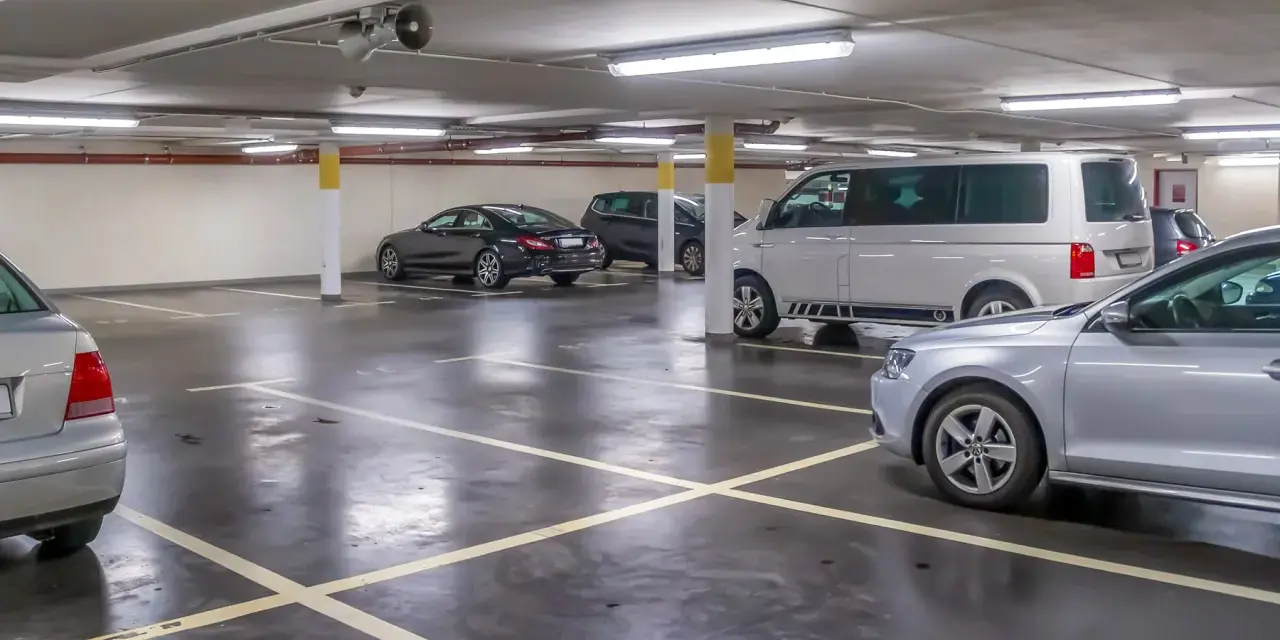 Parcheggio sotterraneo con diverse auto, tra cui un furgone bianco e una berlina nera. Un'auto argentata è in primo piano. Questo è l'ingresso a Venezia per chi arriva in auto.