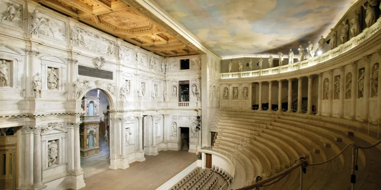 Interno del Teatro Olimpico, gioiello architettonico di una città veneta, con statue, colonne e un soffitto affrescato.
