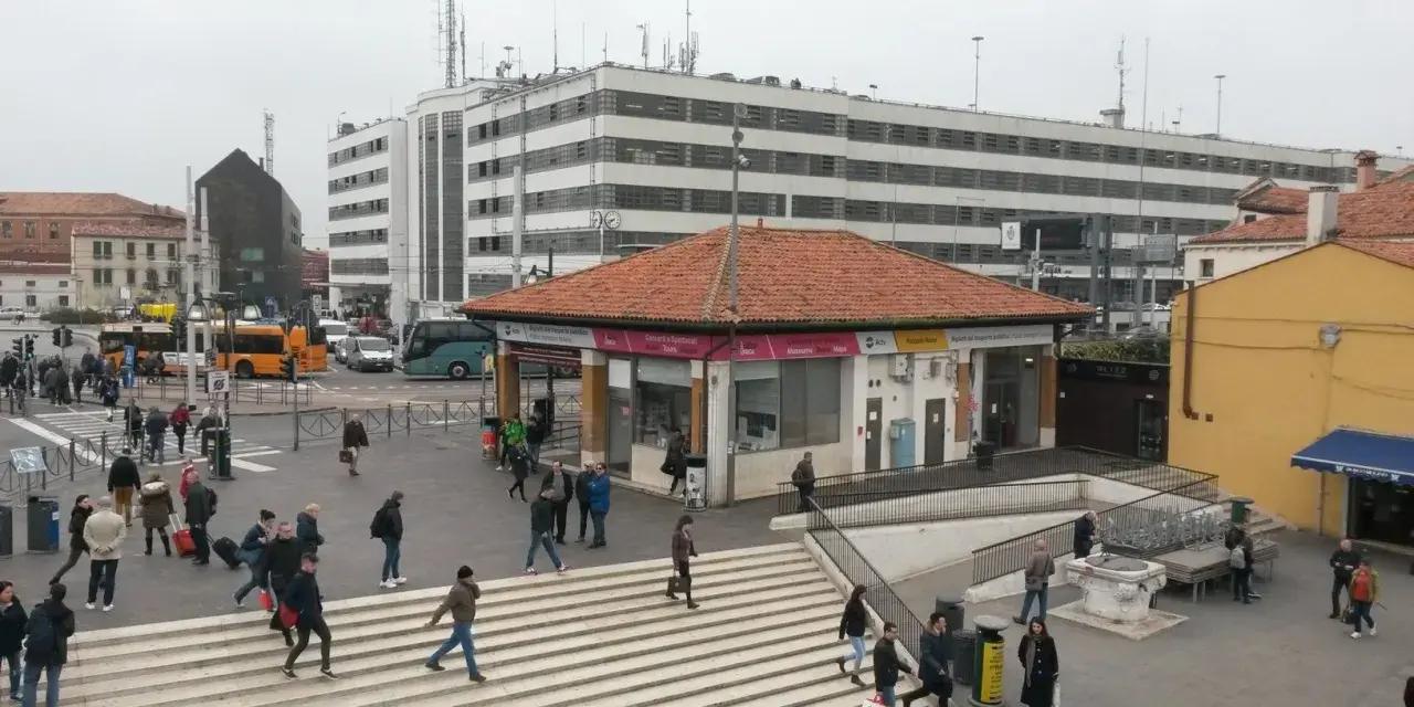 Persone attraversano le scale a Piazzale Roma, vicino a una fermata del vaporetto.