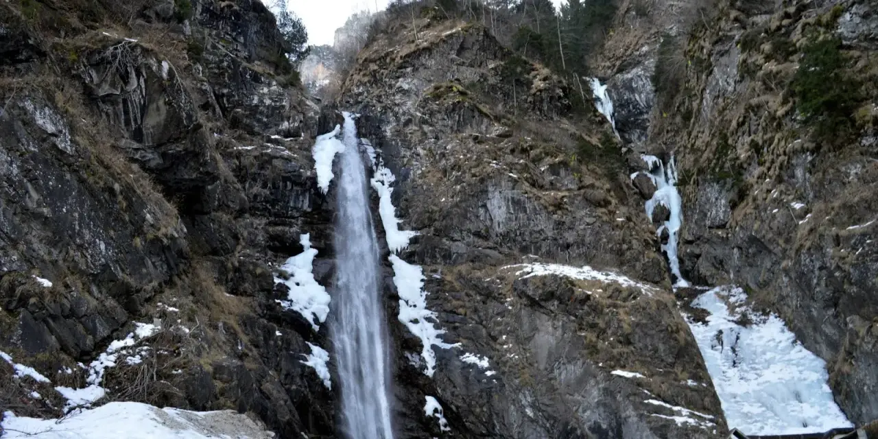Cascate in Veneto, con rocce innevate e ghiaccio che scende lungo i fianchi della montagna.