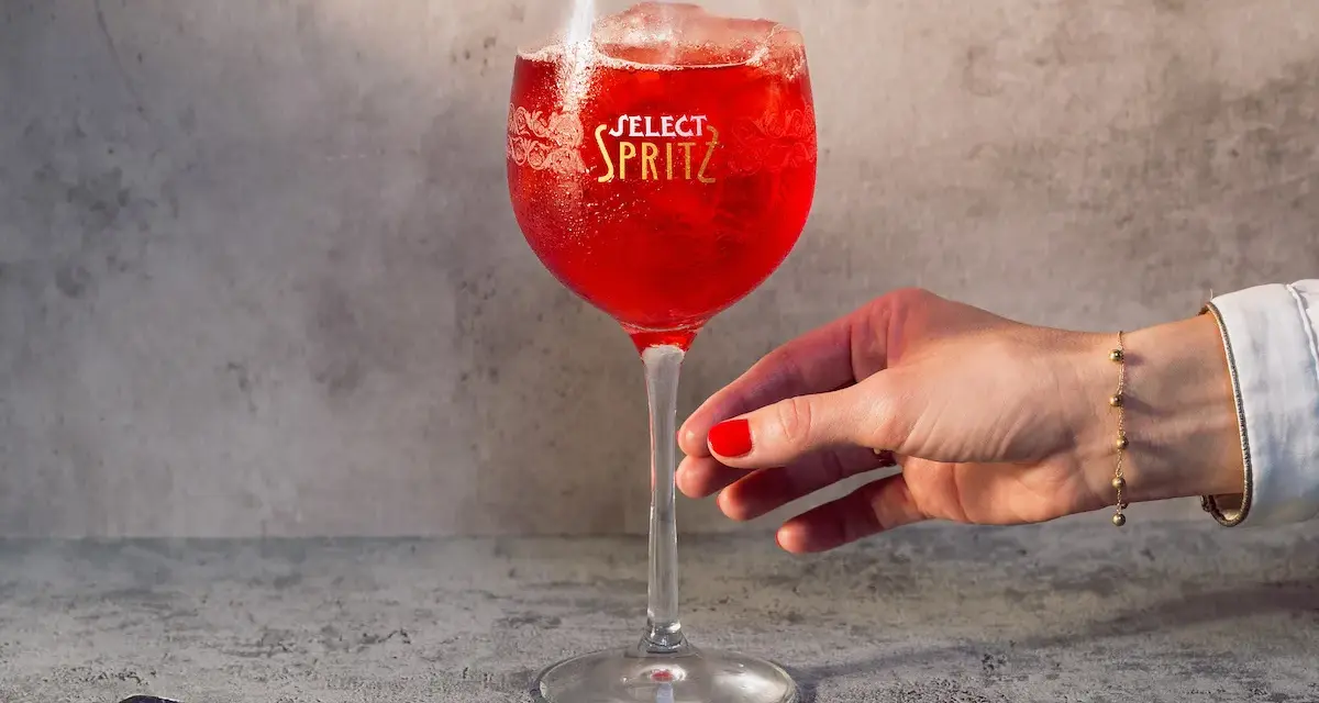 Un bicchiere di Spritz Select, con oliva e ghiaccio, pronto per essere gustato. Un tocco di Venezia in ogni sorso.