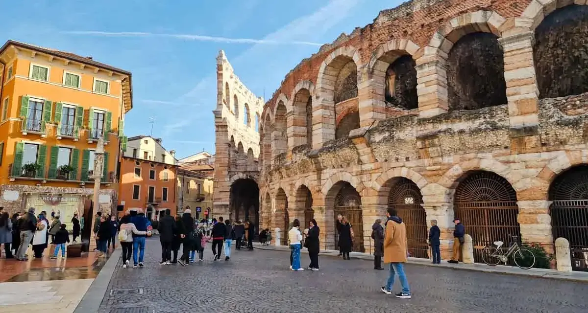 L'arena di Verona interno, con la sua maestosa struttura in pietra e archi, fa da sfondo a una piazza animata da turisti.