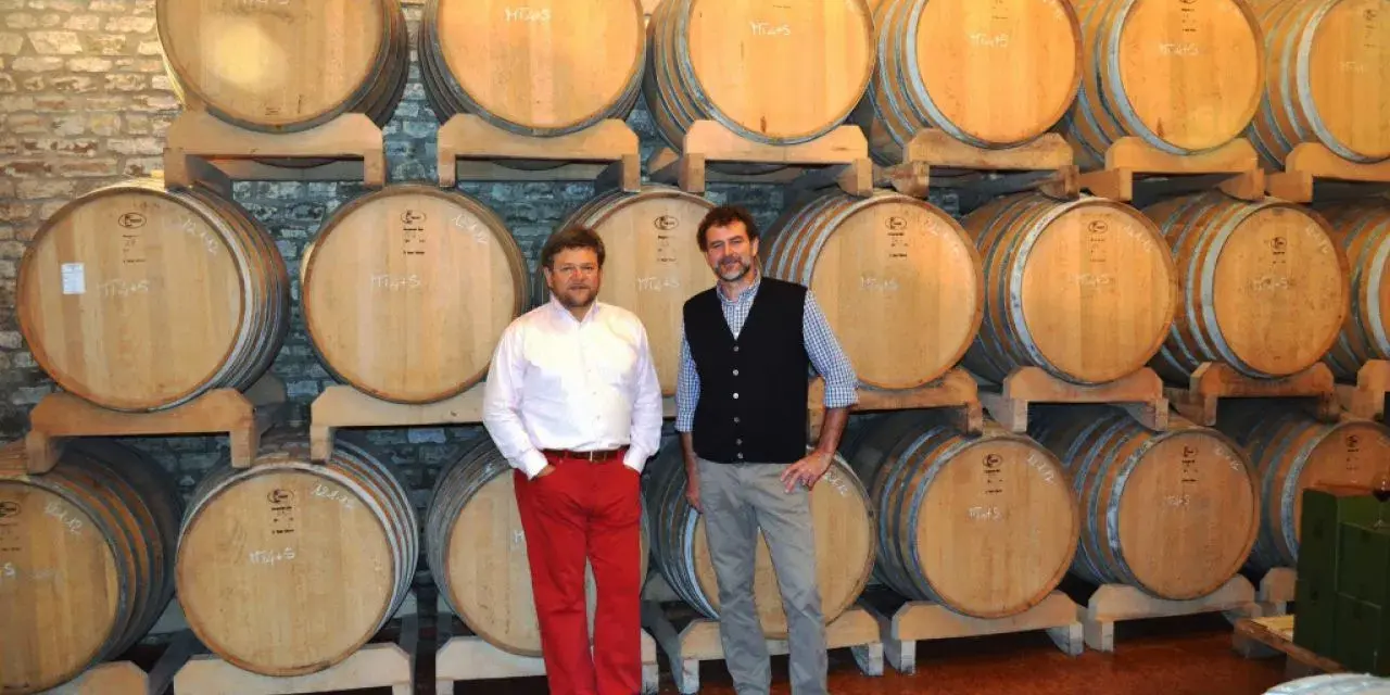 Due uomini in una cantina con botti di legno, simbolo delle migliori cantine dei Colli Euganei.