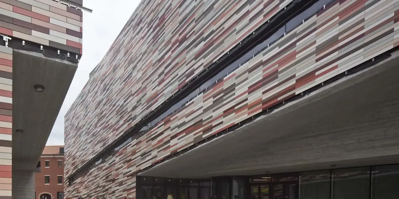 Il museo M9 a Mestre, con la sua facciata a listelli colorati, accoglie visitatori sotto un'imponente pensilina in cemento.