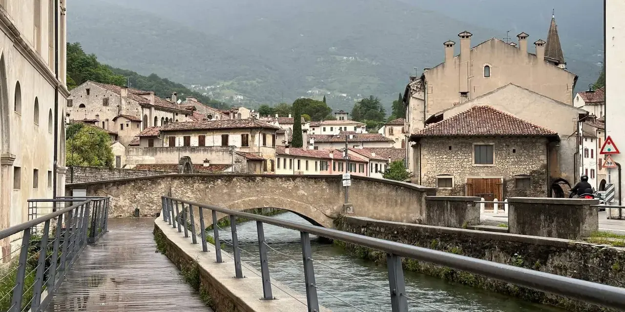 Passeggiata lungo il canale, tra antichi palazzi e ponti in pietra. Ecco cosa vedere a Vittorio Veneto, con le montagne sullo sfondo.