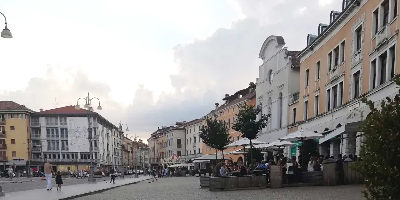Passeggiata serale in piazza a Belluno, cosa vedere: palazzi storici, locali all'aperto e gente che si gode la serata.