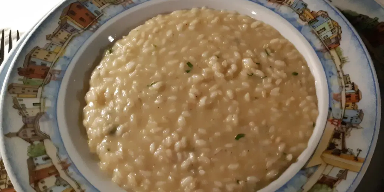 Un cremoso risotto di go Burano, servito in un piatto decorato con le case colorate dell'isola.