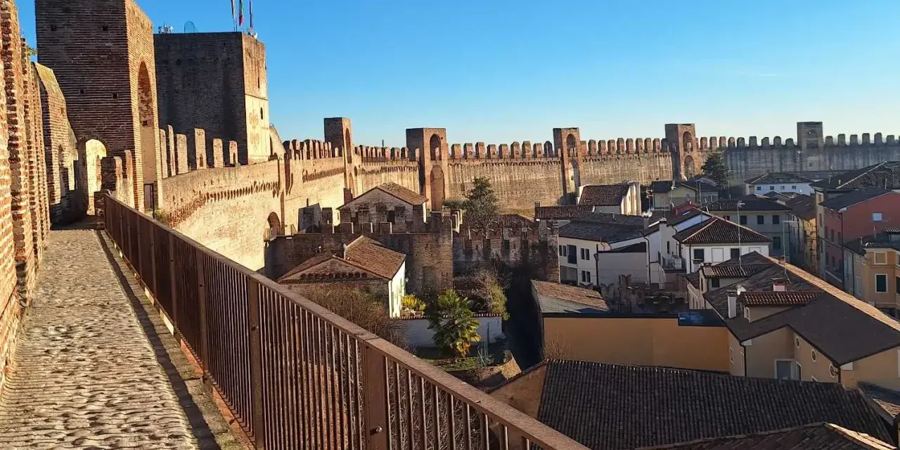 Passeggiata sulle mura della **cittadella** di Padova, con vista sui tetti e le torri medievali sotto un cielo azzurro.