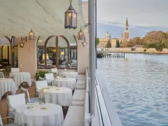 Terrazza elegante di uno dei ristoranti famosi a Venezia, con tavoli apparecchiati e vista sul canale e sulla città.
