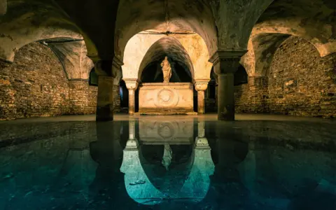 Sotterranei di Venezia misteriosa, con statue e riflessi sull'acqua.