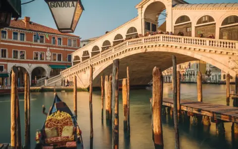 Gondola ferma in un canale di Venezia inverno, con il Ponte di Rialto sullo sfondo.