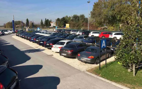Parcheggio con auto moderne, forse vicino a Venezia Mestre o Santa Lucia. Un cartello blu con la "A" indica un'area di sosta.